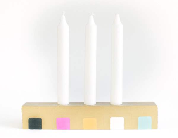 White Colored Candles which are Placed in Yellow Blocks with Several Colorful Painting